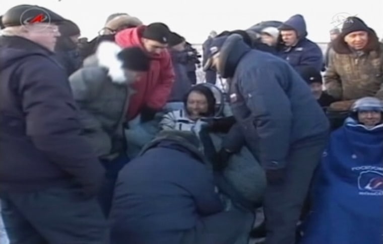 NASA astronaut Michael Fossum is bundled up after his extraction from a Soyuz capsule, just after the end of his homeward trip from the International Space Station. Russian cosmonaut Sergei Volkov can be see at the right edge of the image, wearing a helmet.